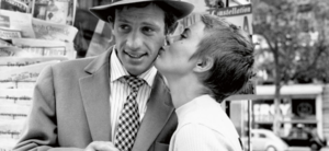 Mann med hatt og kvinne som kysser han på kinnet. 